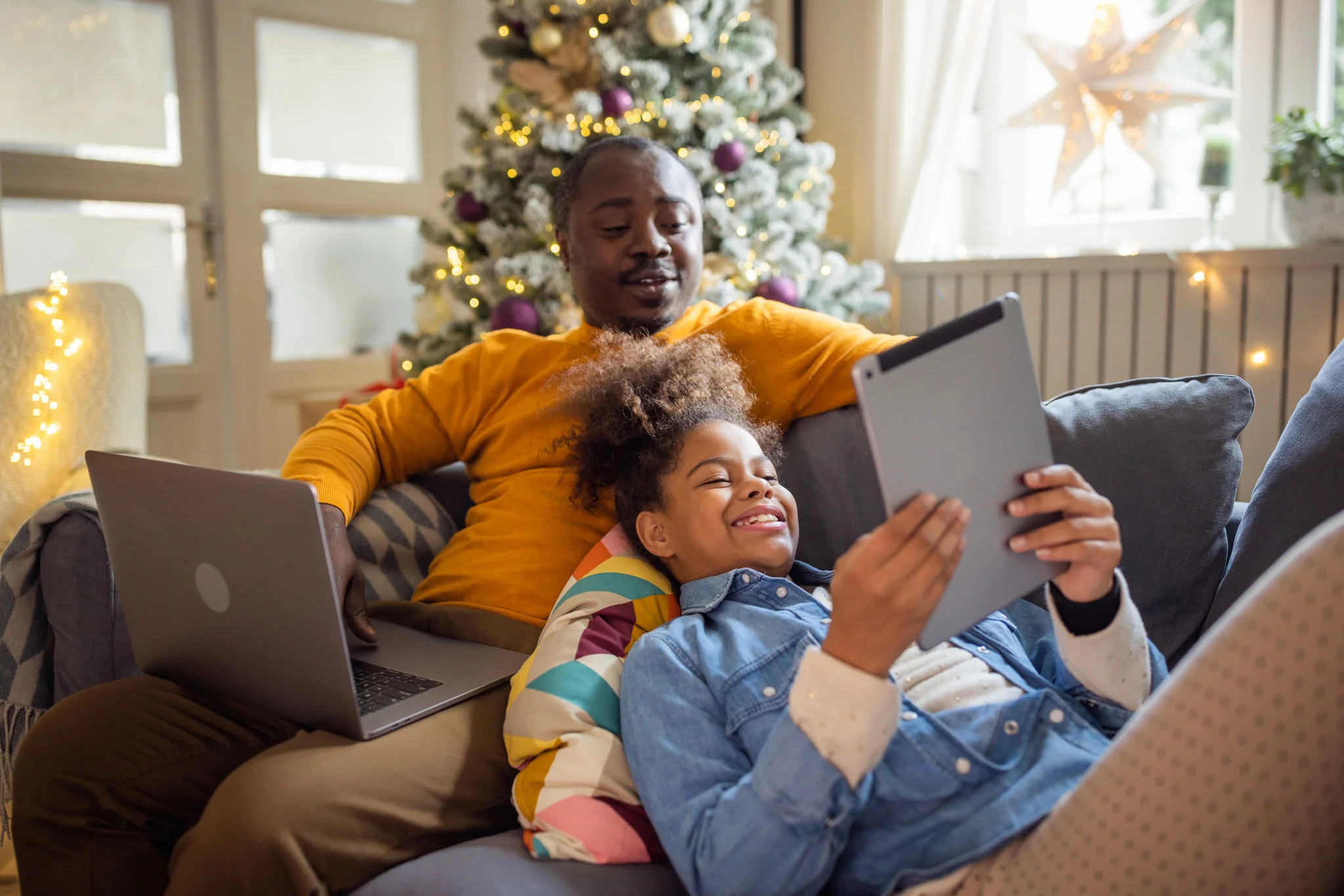 two people on sofa with electronics