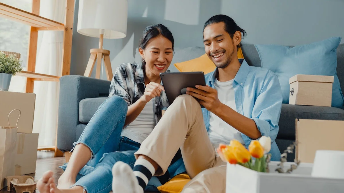 A couple looking at a tablet device in a new home.