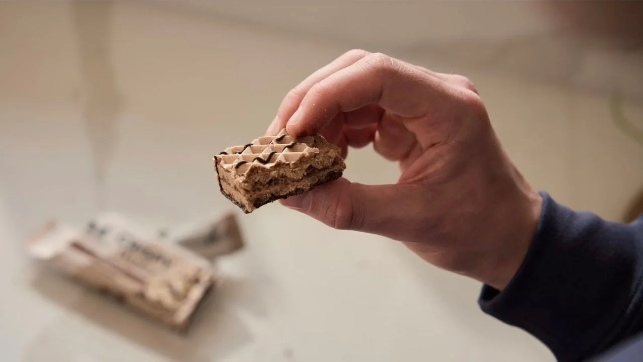 Hand holding a piece of a protein wafer bar.