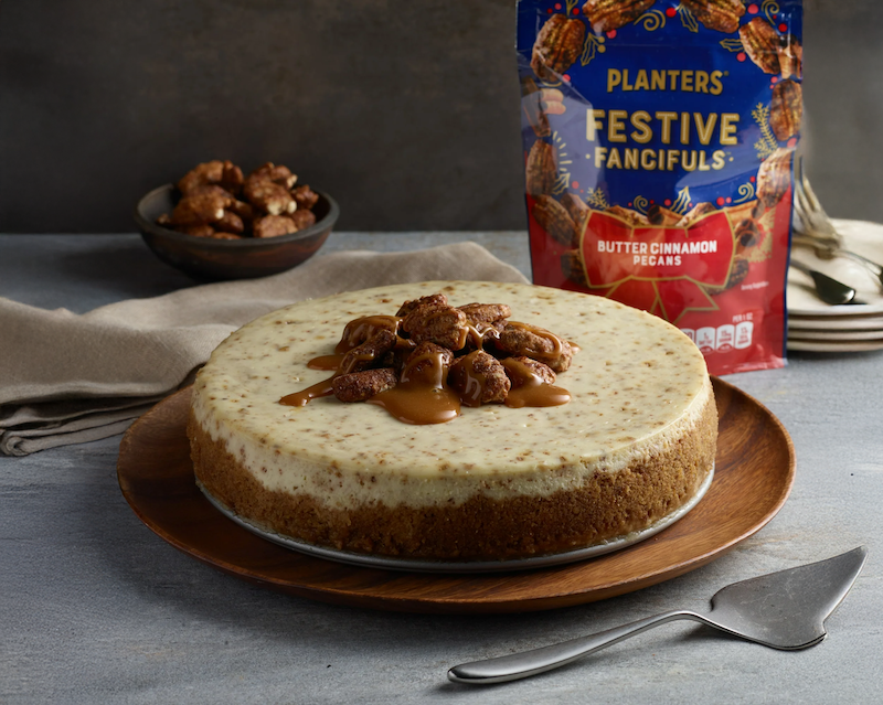Planters Festive Fancifuls butter cinnamon pecans on cheesecake with product bag in background.